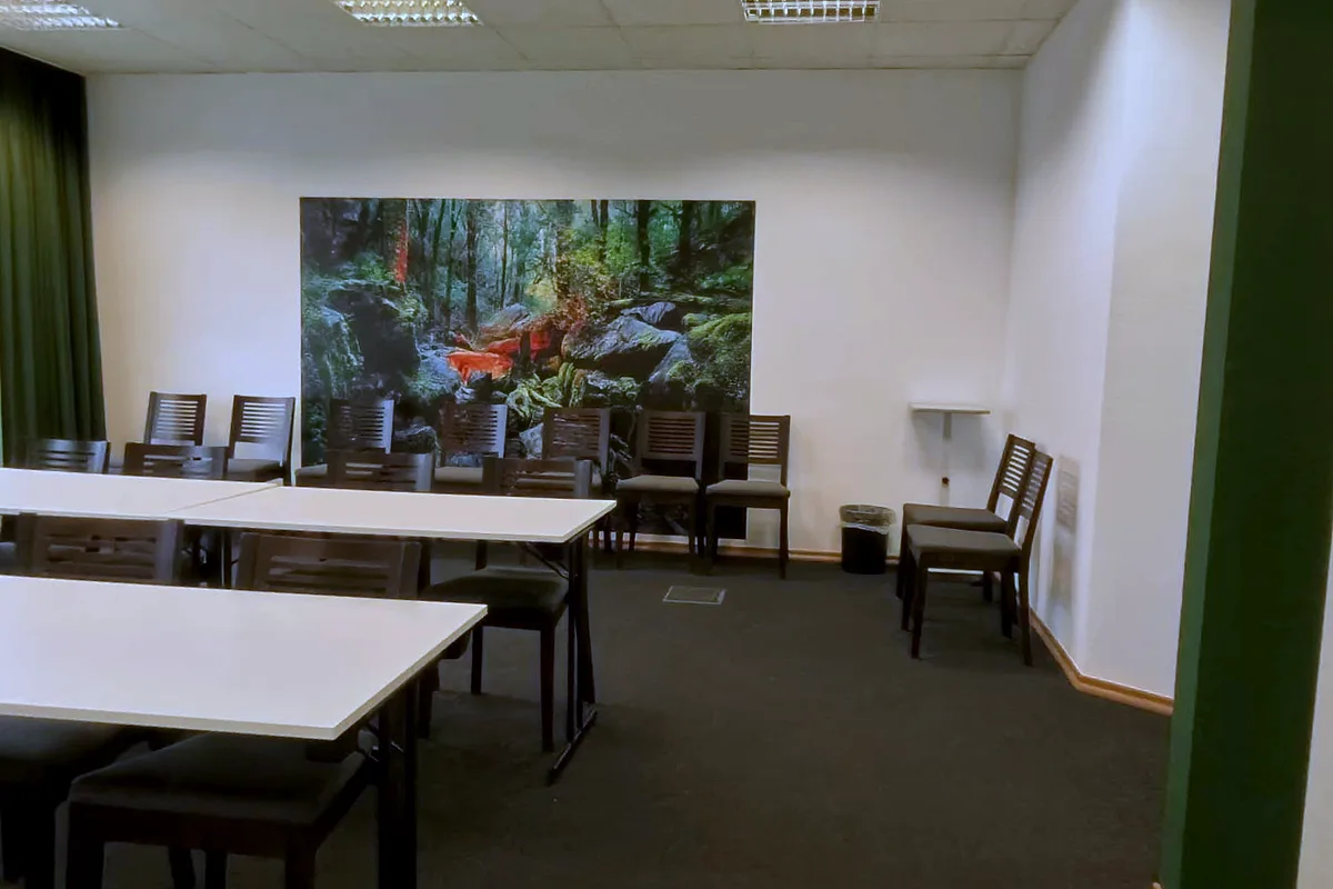 The Hennef room at EURO PARK HOTEL Hennef: white tables, dark wooden chairs and a large forest photo mural, with the green archway on the right