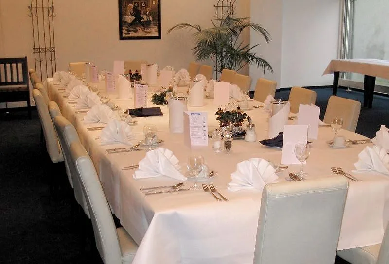 Lange Tafel im EURO PARK HOTEL Hennef, ruhig in Weiß eingedeckt mit gefalteten Servietten, Menükarten, kleinen Gestecken und hellen Stühlen