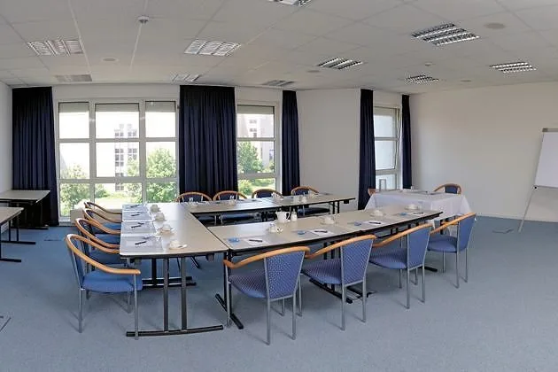 Koblenz meeting room at EURO PARK HOTEL Hennef: U-shaped tables with blue chairs, dark blue curtains, a flipchart and a wide wall of windows